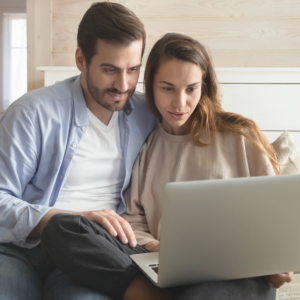 a couple sitting together and looking at a laptop