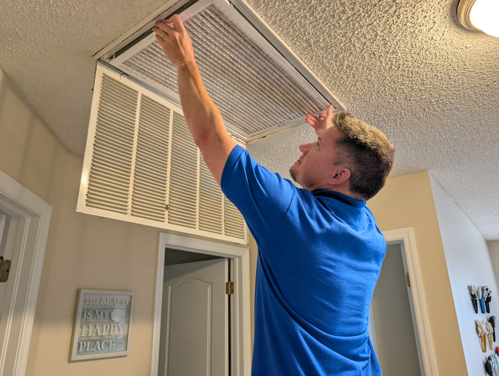 Person taking out an HVAC filter in the ceiling.