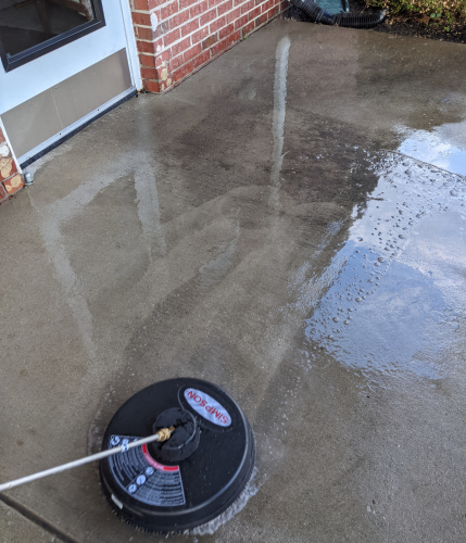 pressure washing dirt off of a concrete sidewalk
