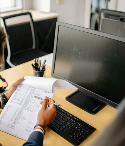 person sitting at desk with computer reviewing a document