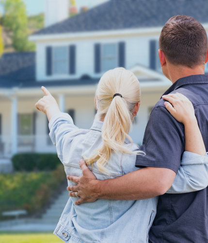couple facing a two story white house with black shutters